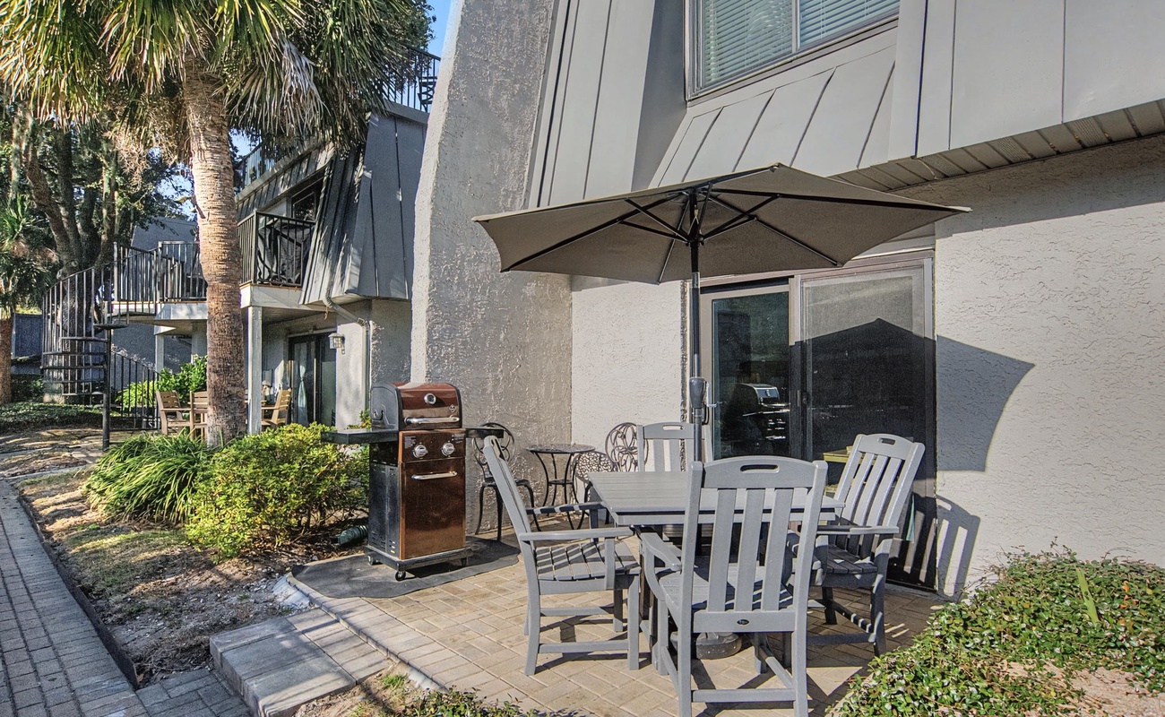 Your private patio awaits with comfortable dining seating, BBQ grill, and tropical palm shade for perfect outdoor meals.