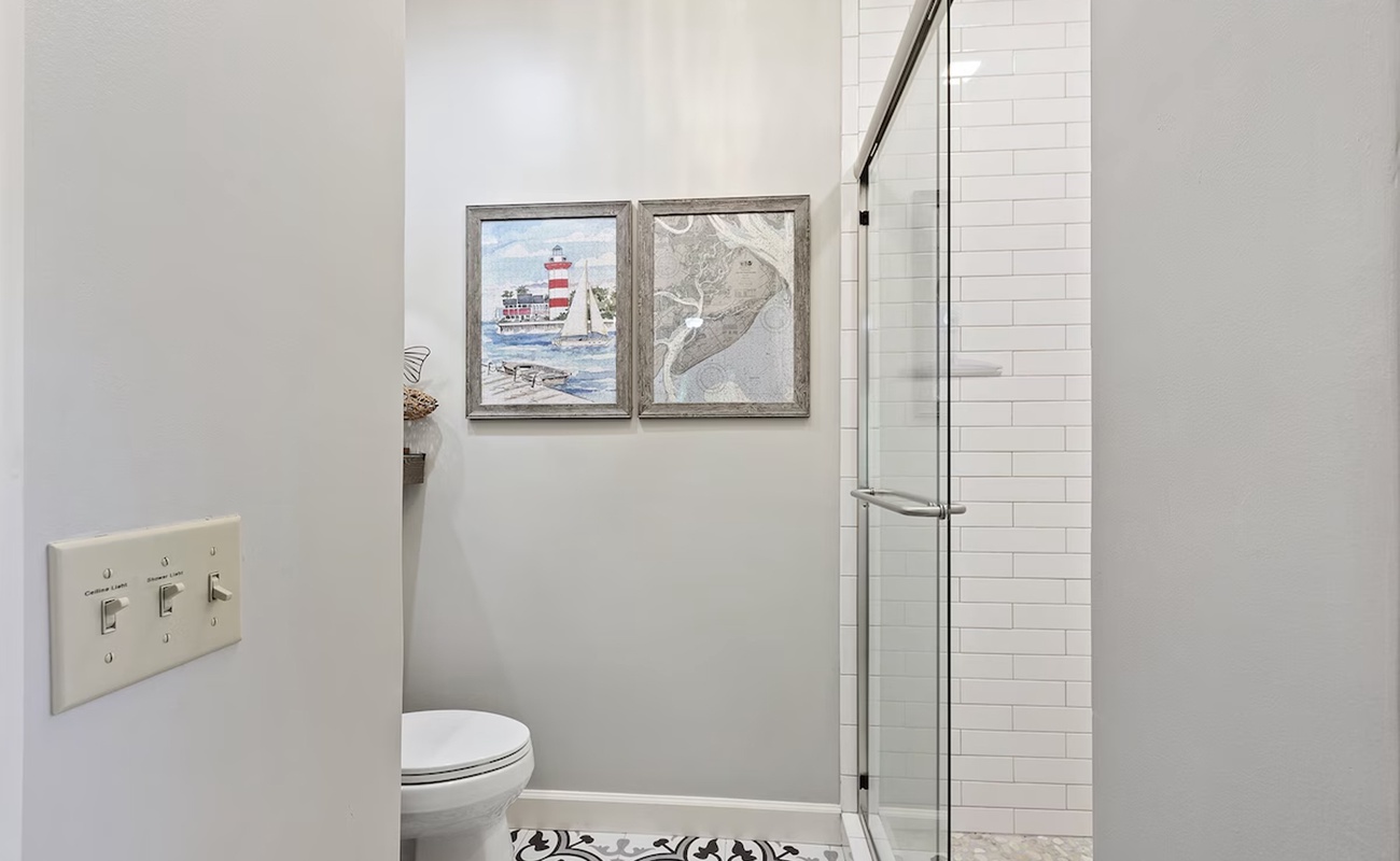 Step into your modern bathroom retreat with elegant subway tile shower and coastal artwork creating a serene atmosphere.