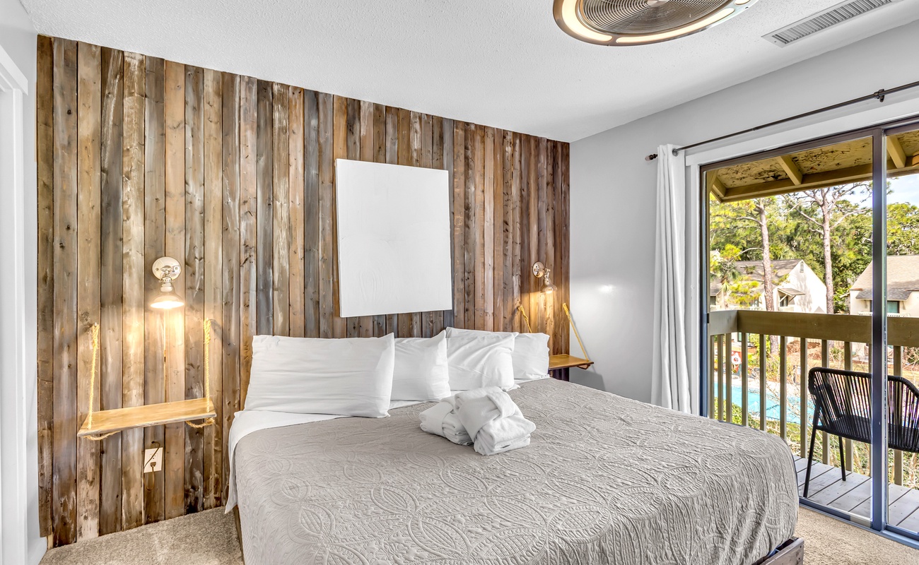 Drift off in your cozy bedroom featuring rustic wood accents, crisp linens, and a private balcony overlooking the pool.