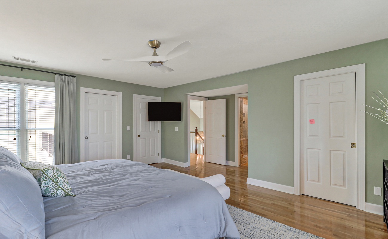 Unwind in your spacious master suite with calming sage walls, gleaming hardwood floors, and ceiling fan for perfect comfort.