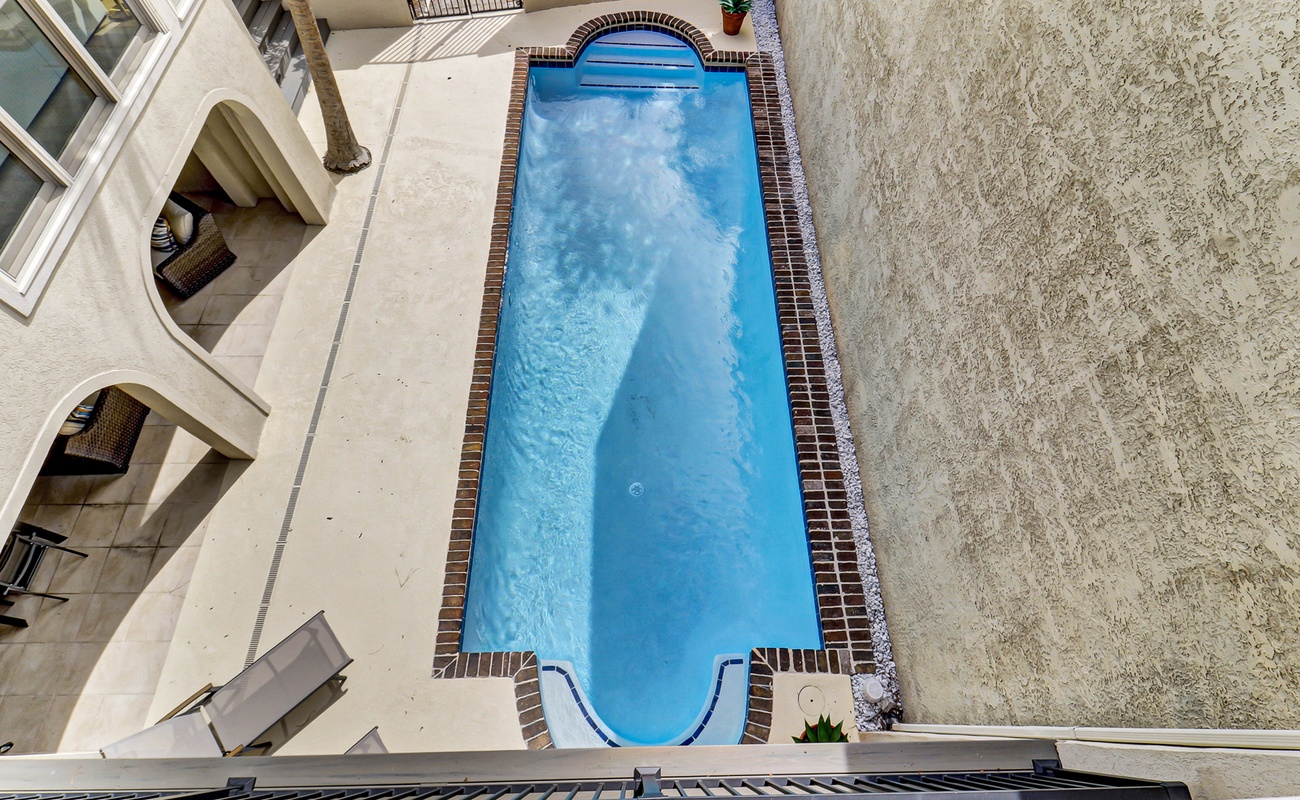 Aerial view of the property's private swimming pool and outdoor terrace area with decorative brick tile edging.