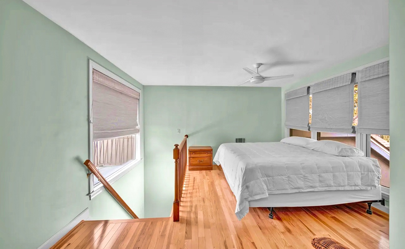 Unwind in your serene bedroom featuring calming mint walls, warm timber floors, and crisp white linens that invite peaceful sleep.