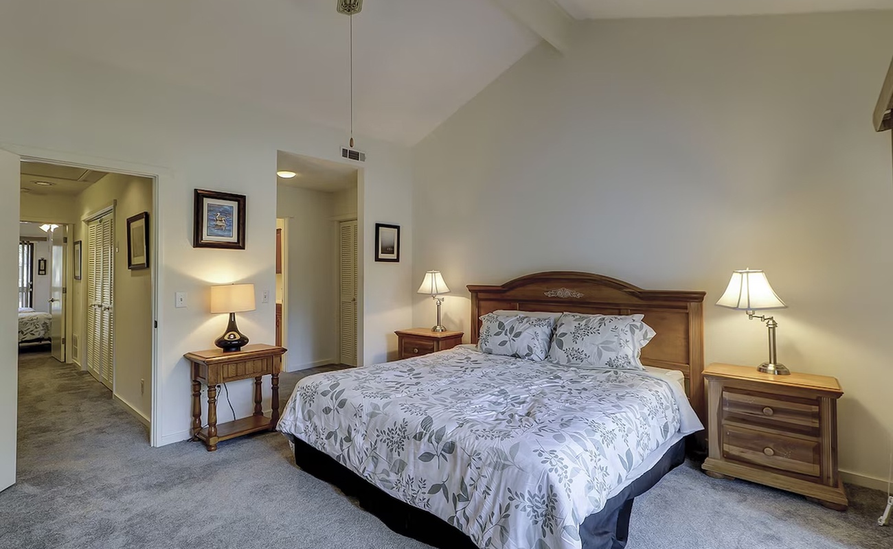 Sink into your plush bed with elegant botanical linens, surrounded by warm wood furnishings and soft lamplight creating the perfect retreat.