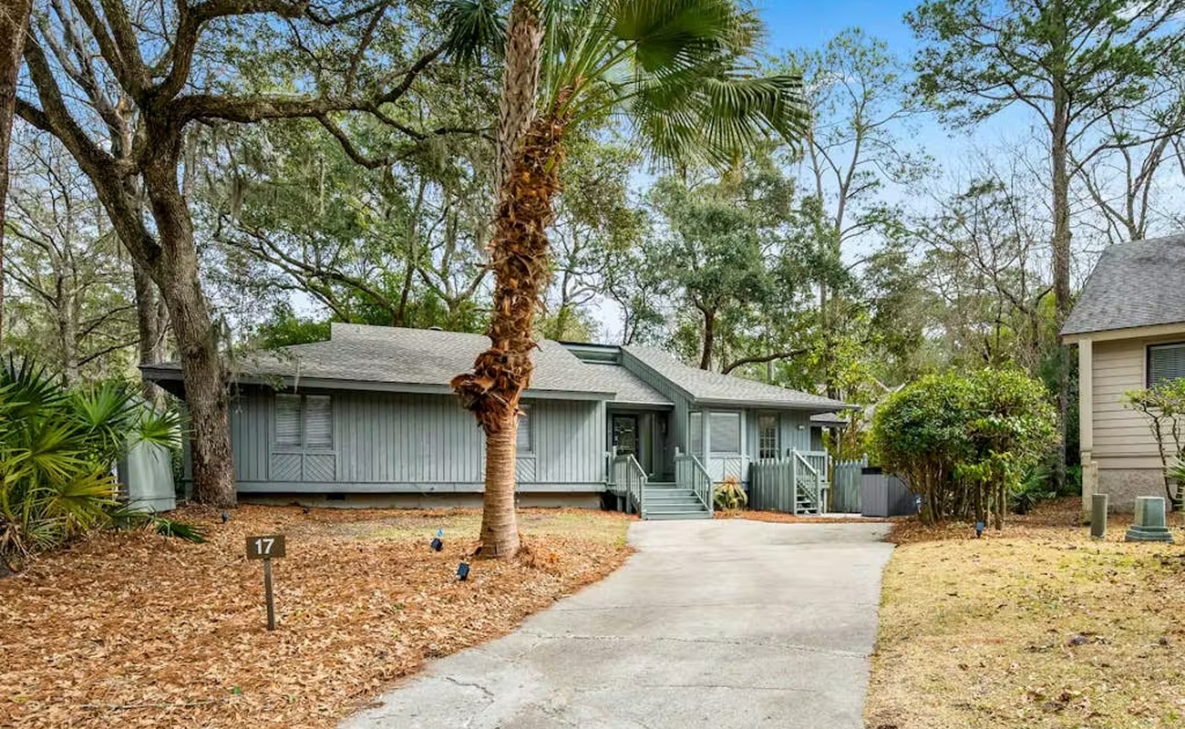 Charming coastal retreat nestled among mature trees and tropical palms, offering a peaceful escape with convenient parking and welcoming entrance.