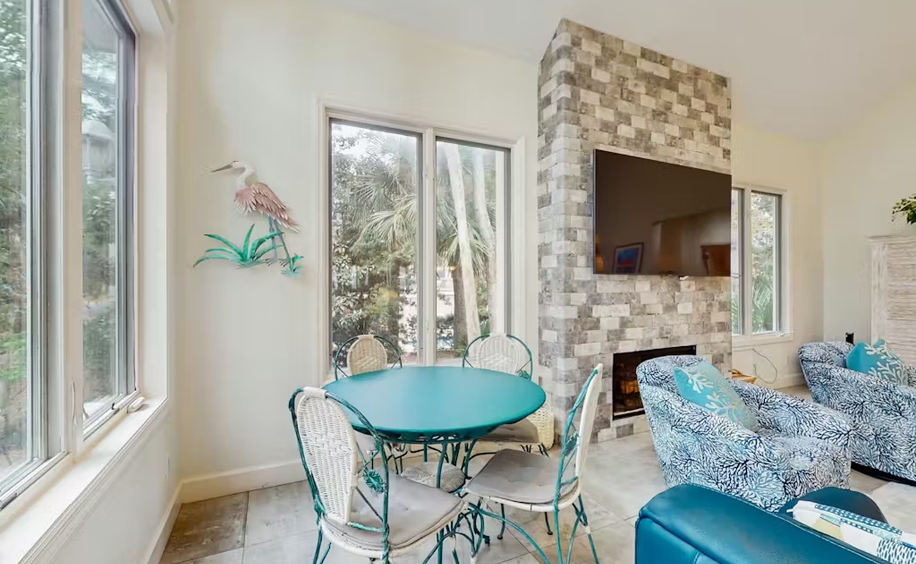 Relax in your bright dining space with cheerful turquoise seating and a cozy fireplace, perfect for memorable meals together.