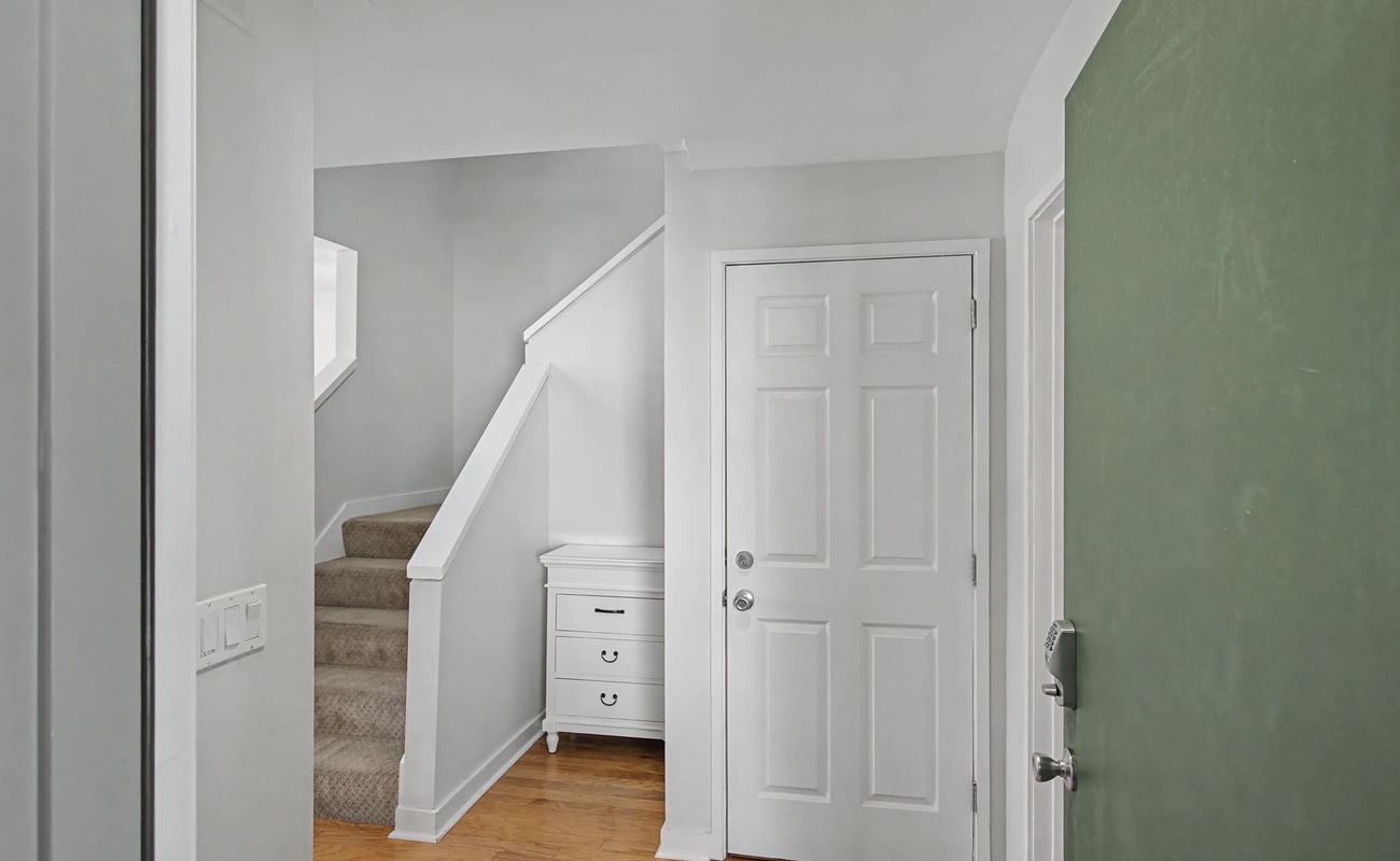 Step into your welcoming entryway with warm hardwood floors and a charming staircase leading to your private upstairs retreat.