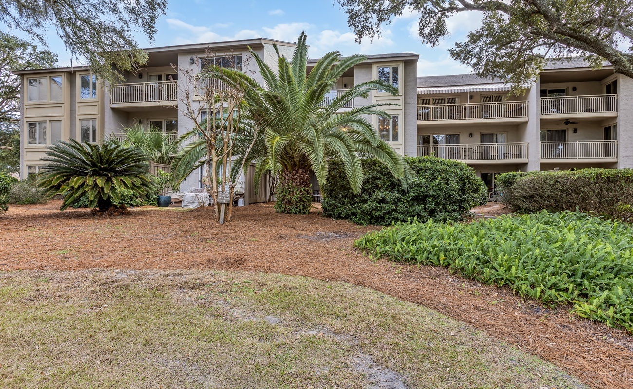 Multi-story vacation property surrounded by tropical landscaping and mature palm trees in a peaceful residential setting.