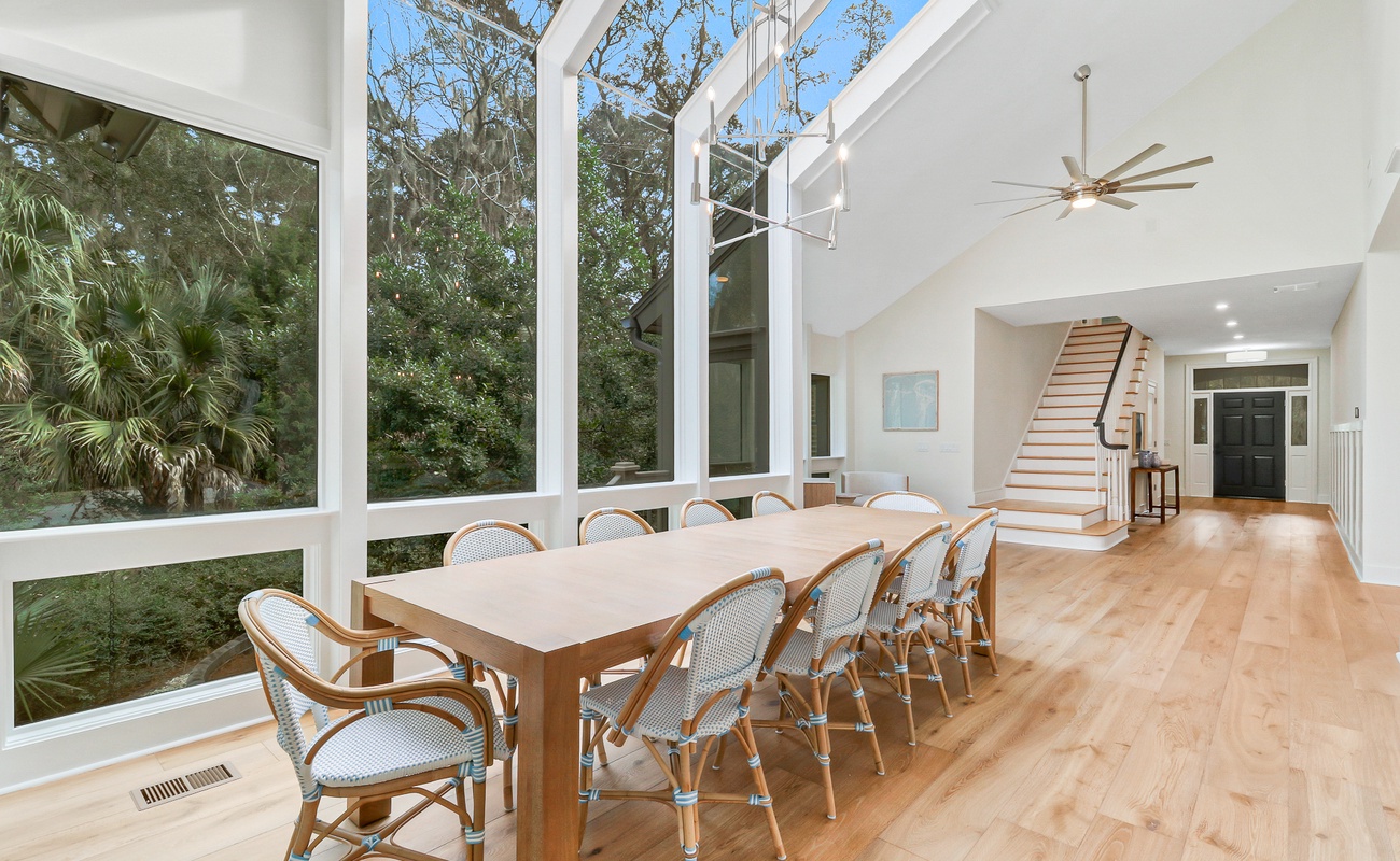 Gather around this elegant dining table where floor-to-ceiling windows frame lush garden views, creating your perfect space for memorable meals together.