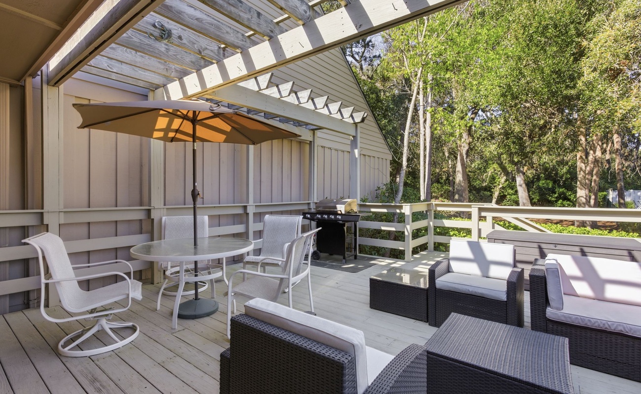 Your private deck beckons with comfy seating, dining space, and BBQ grill surrounded by lush trees.