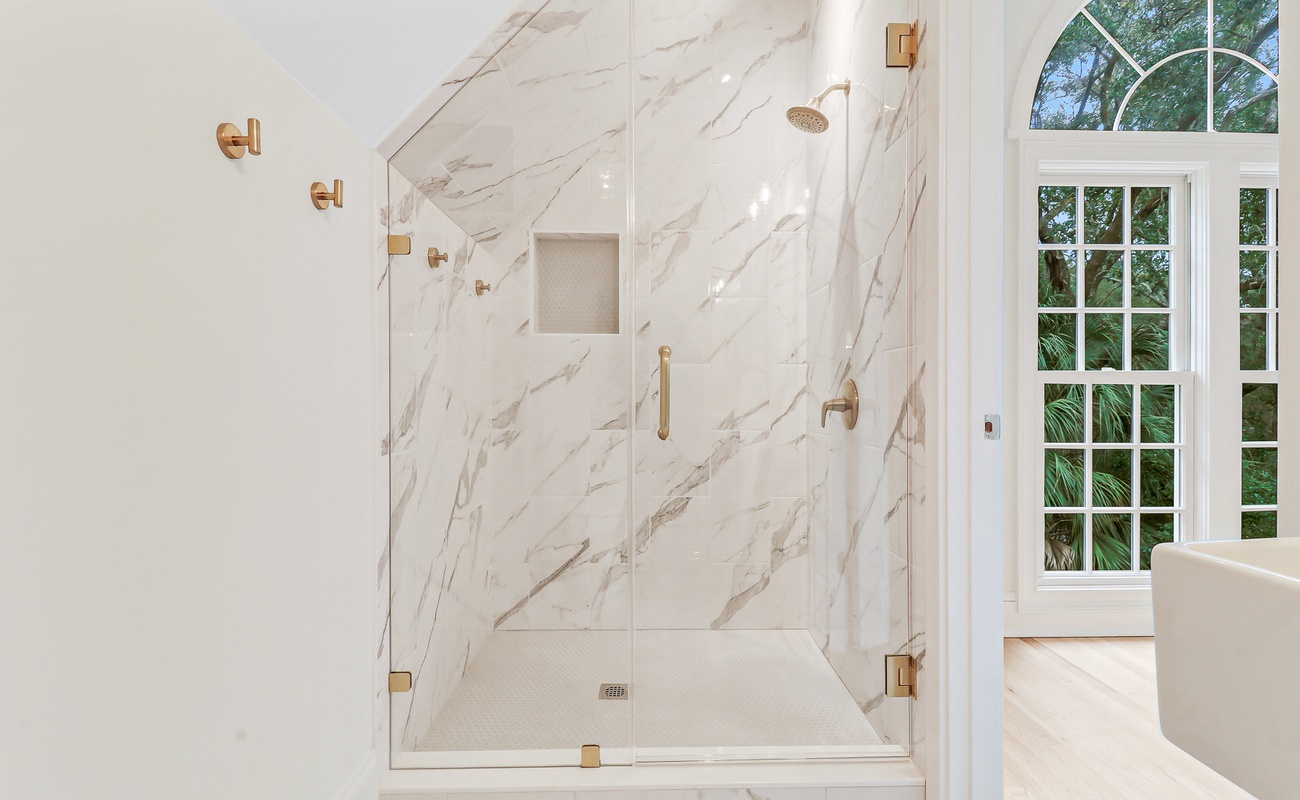 Step into your spa-like marble shower with elegant gold fixtures, where morning light streams through garden windows.