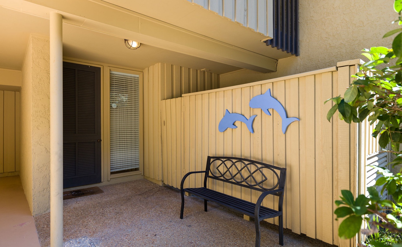 Your private covered patio welcomes you with playful dolphin art and a cozy bench for morning coffee or evening relaxation.