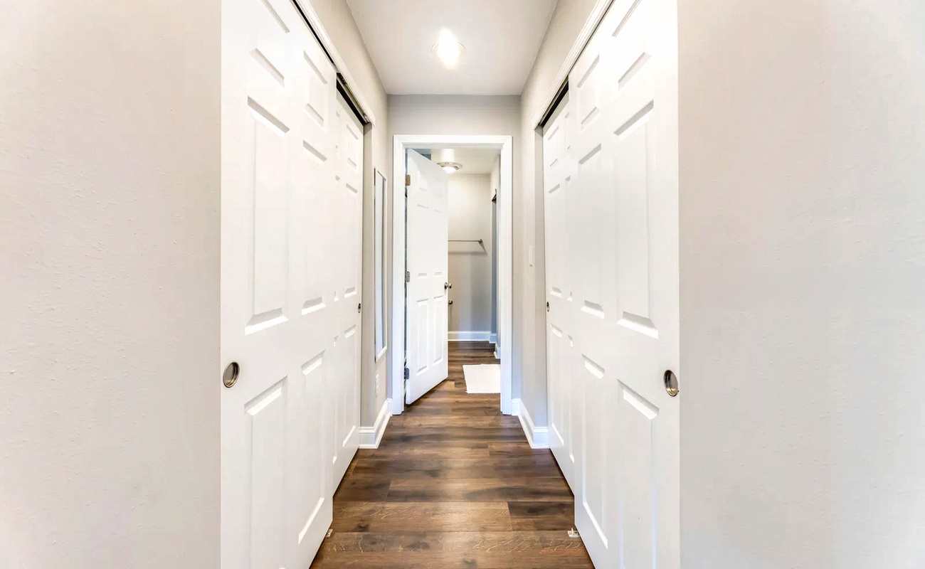 Step into your pristine hallway with gleaming hardwood floors and crisp white doors leading to comfortable spaces throughout.