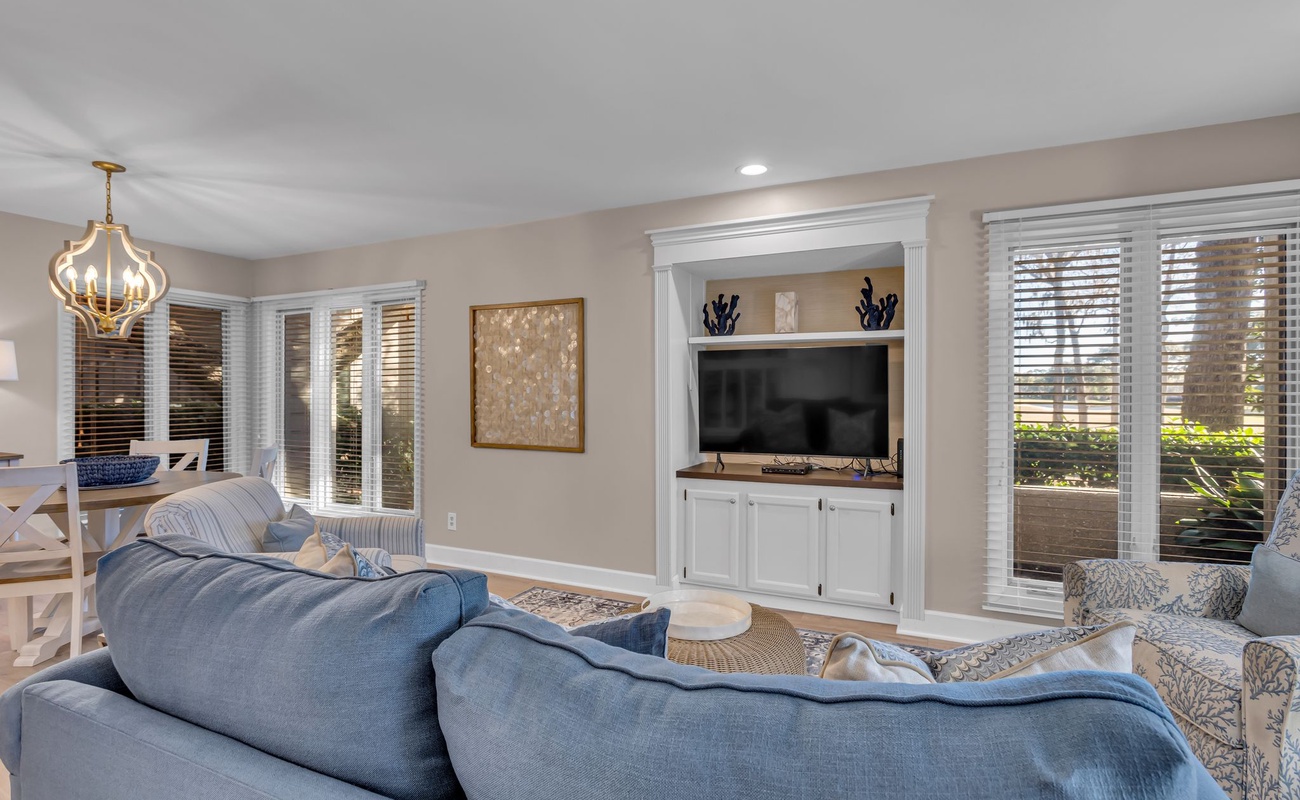 Sink into plush blue sofas and unwind in your elegant living space, complete with built-in entertainment center and charming coastal décor.