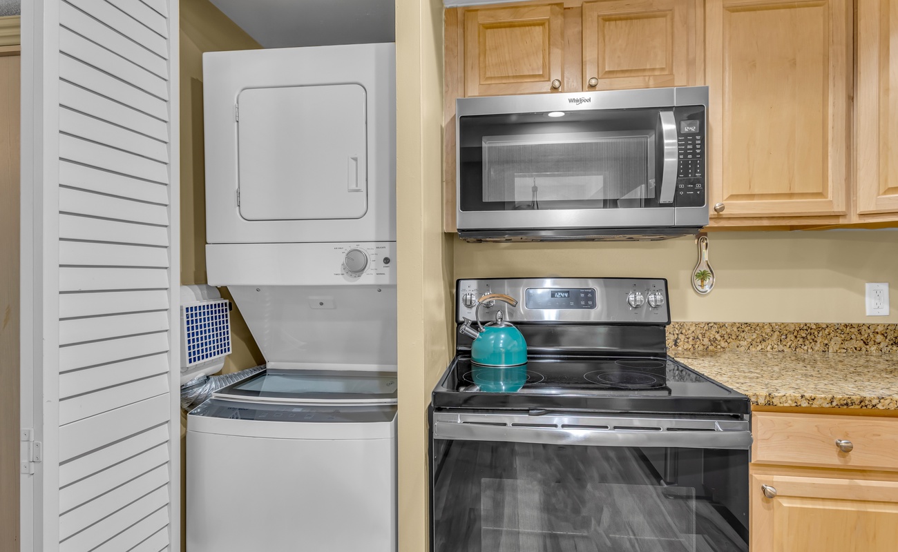 Your fully equipped kitchen features everything you need, including convenient in-unit laundry facilities tucked neatly behind louvered doors for a seamless cooking experience.