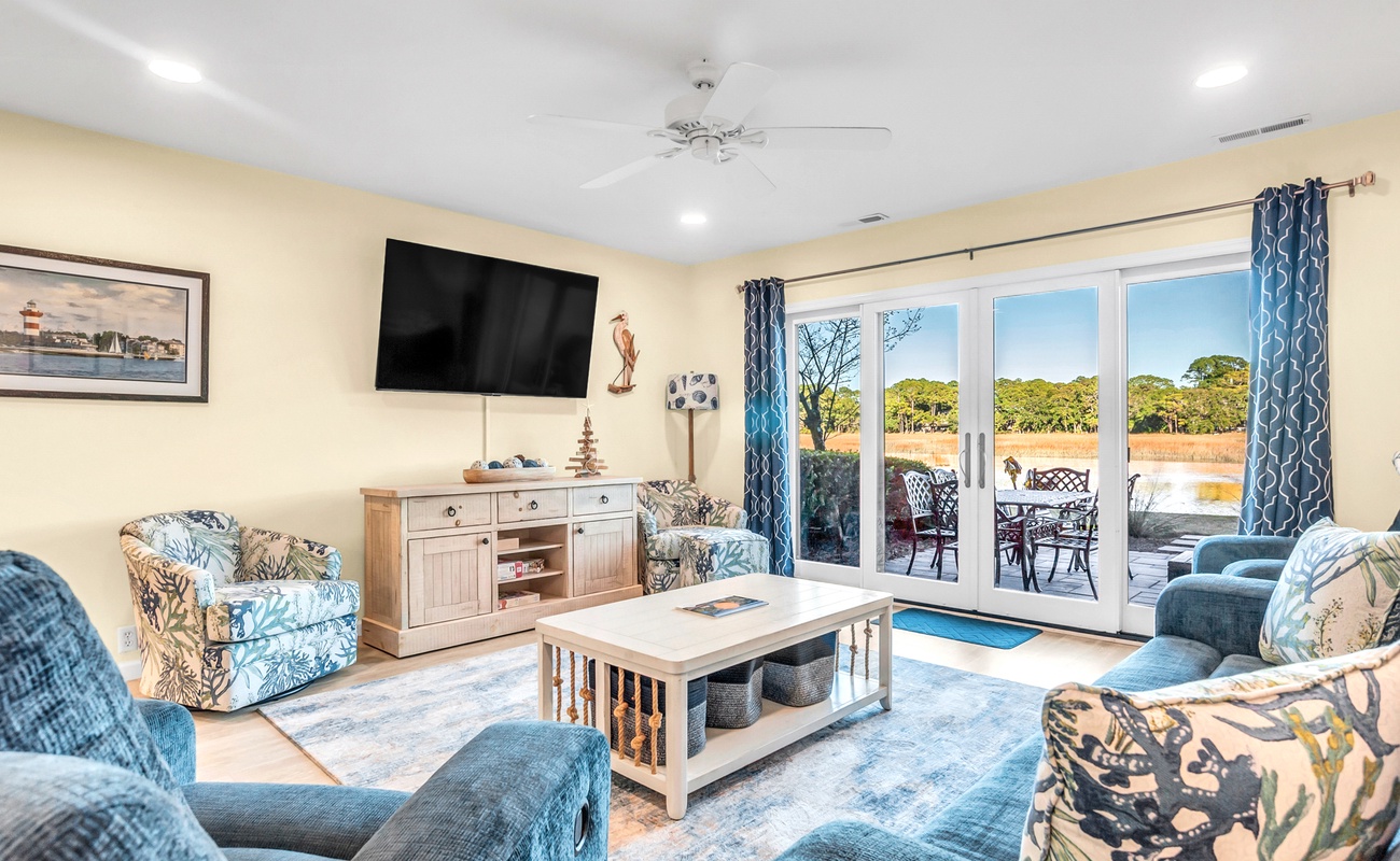 Relax in your spacious living room with coastal décor, perfect for family time and enjoying views of the outdoor dining area.