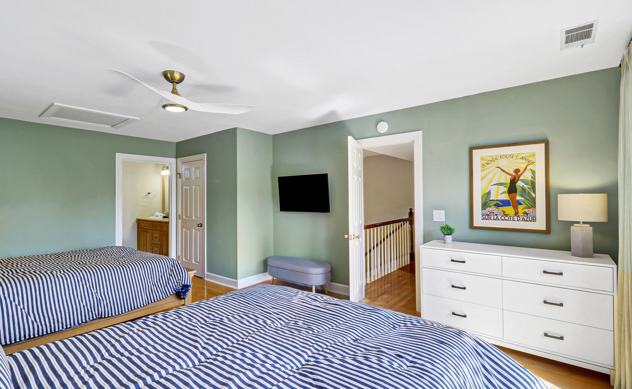 Relax in your serene bedroom with twin beds featuring crisp nautical bedding and coastal artwork setting a peaceful mood.