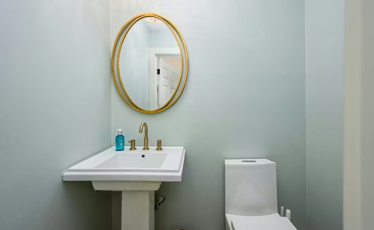 Step into your beautifully appointed powder room with elegant gold-framed mirror and modern fixtures for your comfort.