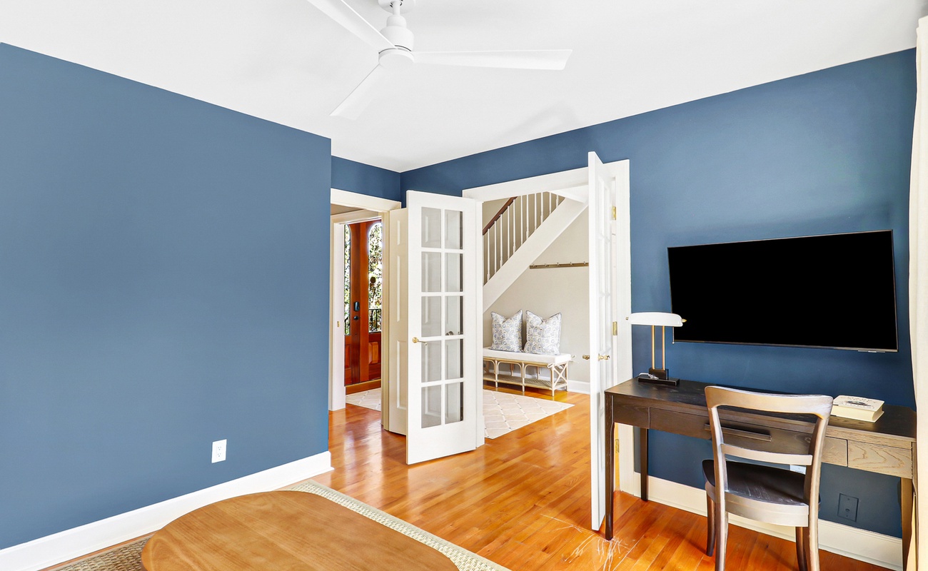 Your private workspace features calming blue walls, rich hardwood floors, and French doors opening to a serene sitting area.