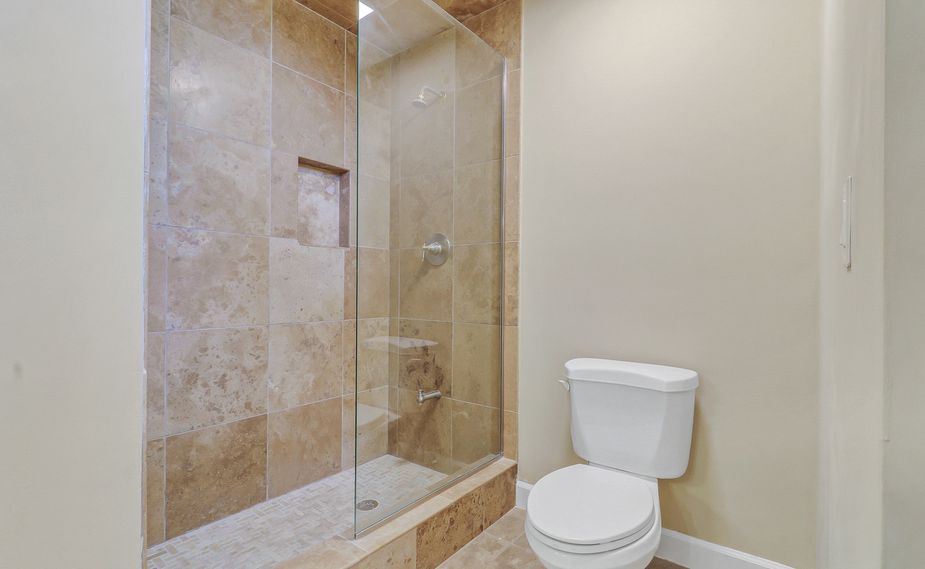 Step into your private bathroom featuring elegant travertine tiles and a spacious glass-enclosed shower perfect for unwinding after your adventures.