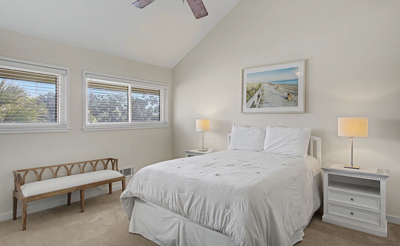 Drift into peaceful slumber in your serene bedroom, complete with plush linens, gentle coastal artwork, and a ceiling fan for perfect comfort.