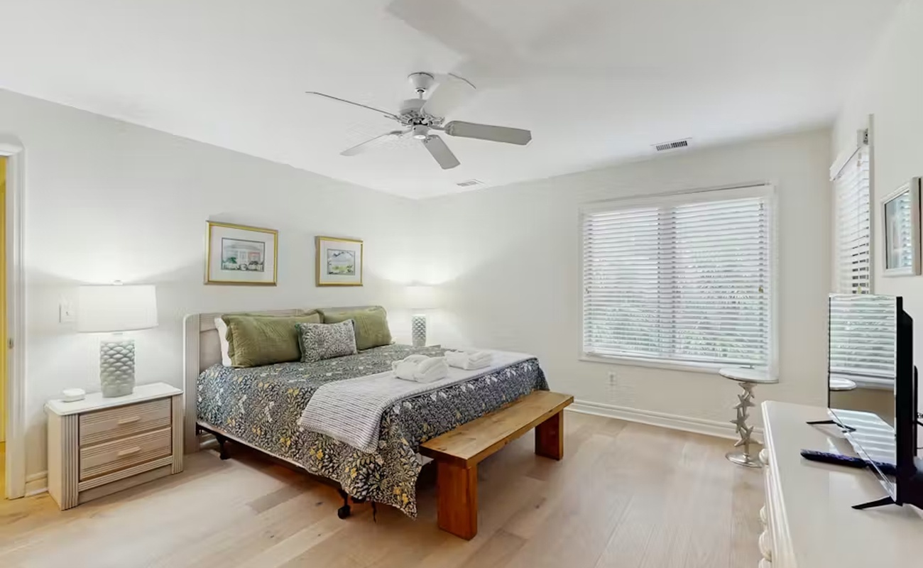 Relax in your serene bedroom sanctuary with natural light, ceiling fan breeze, and peaceful decor creating the perfect retreat.