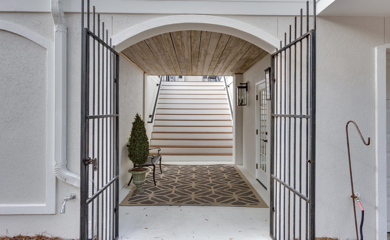 Step through elegant iron gates into your private entrance, where geometric patterns and warm wood details create a welcoming arrival experience.
