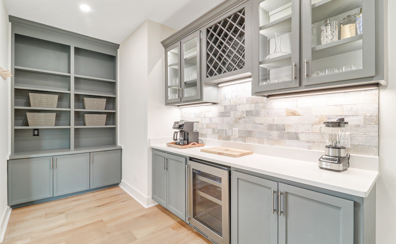 Your elegant butler's pantry features sage green cabinetry, wine storage, and marble countertops perfect for entertaining prep.