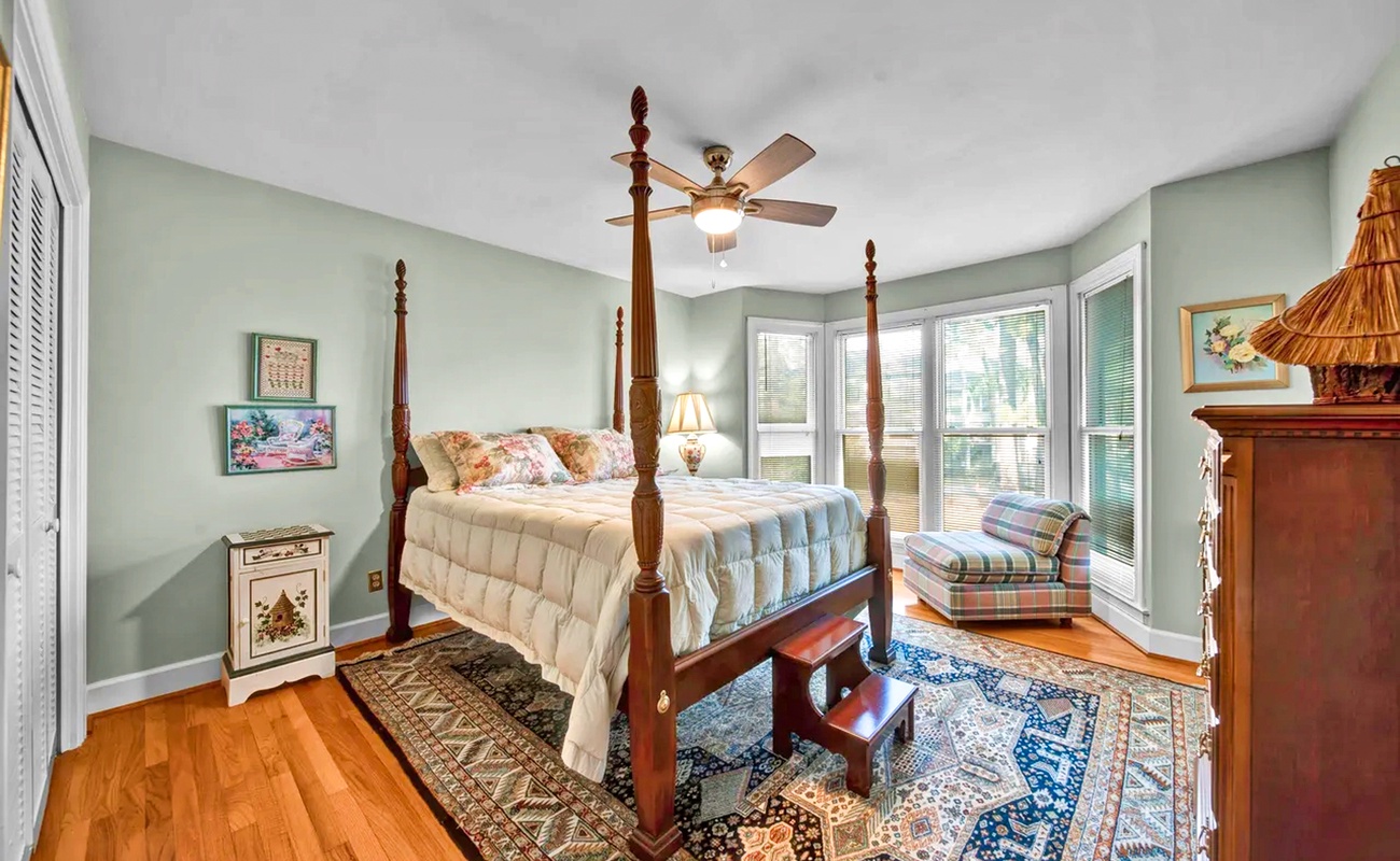 Rest peacefully in your elegant four-poster bed, surrounded by soothing mint walls and warm wood floors that create the perfect retreat.