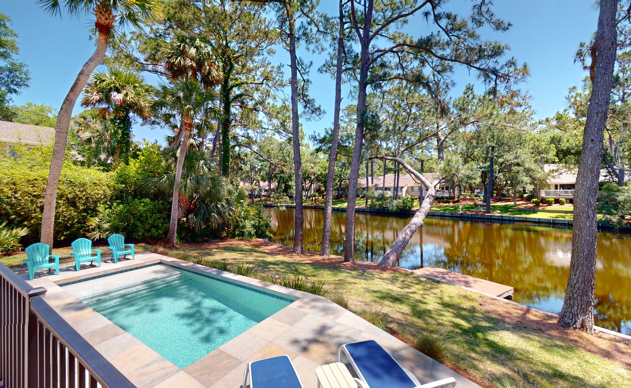 Your private pool overlooks tranquil waterfront views, surrounded by towering pines and palm trees for the perfect peaceful retreat.