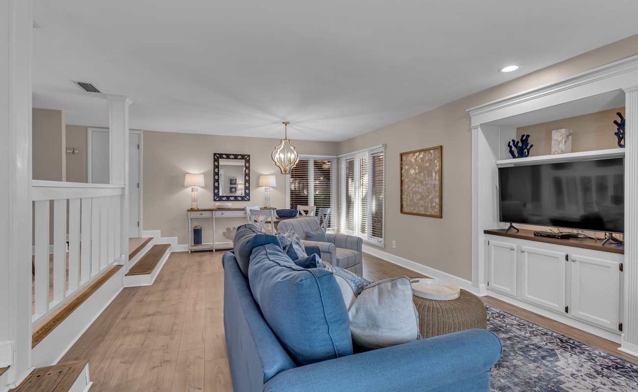 Sink into plush blue sofas in your elegant living space, where warm lighting and built-in entertainment center create the perfect gathering spot.