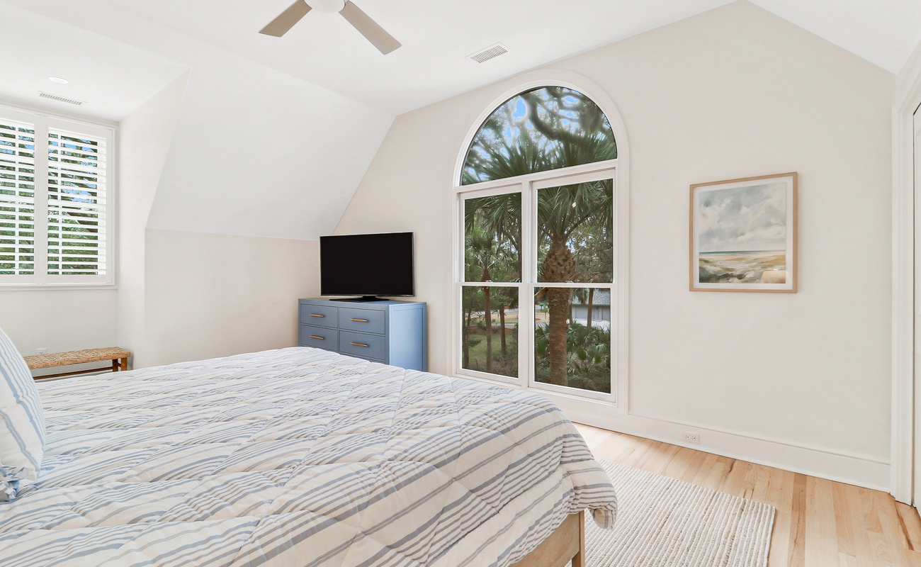 Wake up in your peaceful coastal retreat with palm tree views and gentle sea breezes through the arched window.