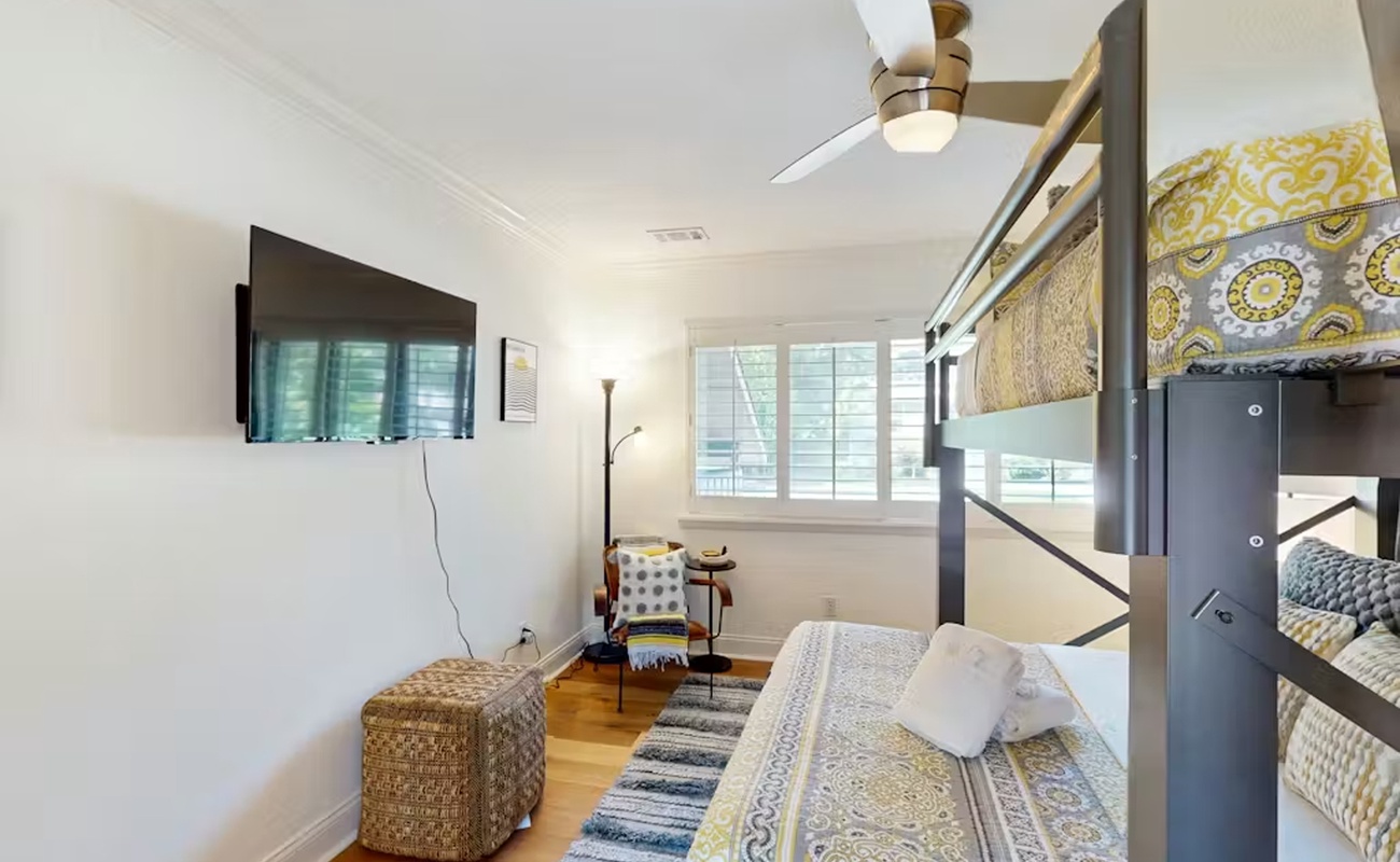 Your cozy bedroom features bunk beds, wall-mounted TV, and cheerful patterns that create a welcoming space for rest.