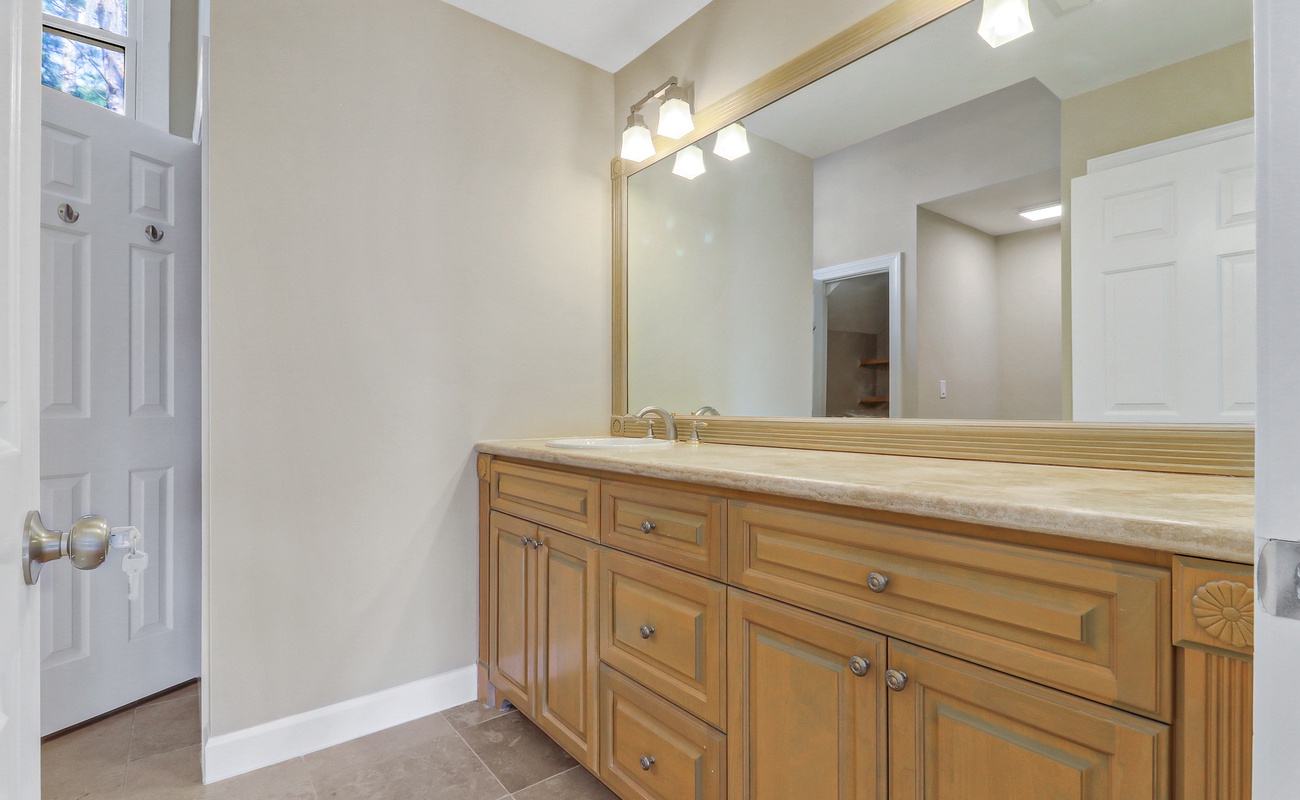 Fresh up in your spacious bathroom with warm wood vanity, ample storage, and bright lighting for your morning routine.