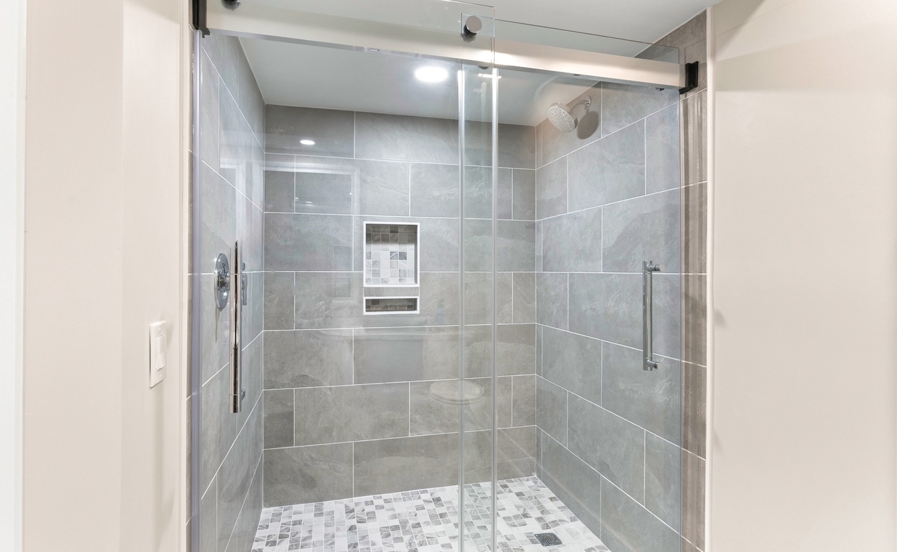 Step into your sleek glass-enclosed shower with rainfall head and modern tiles for your perfect morning refresh.