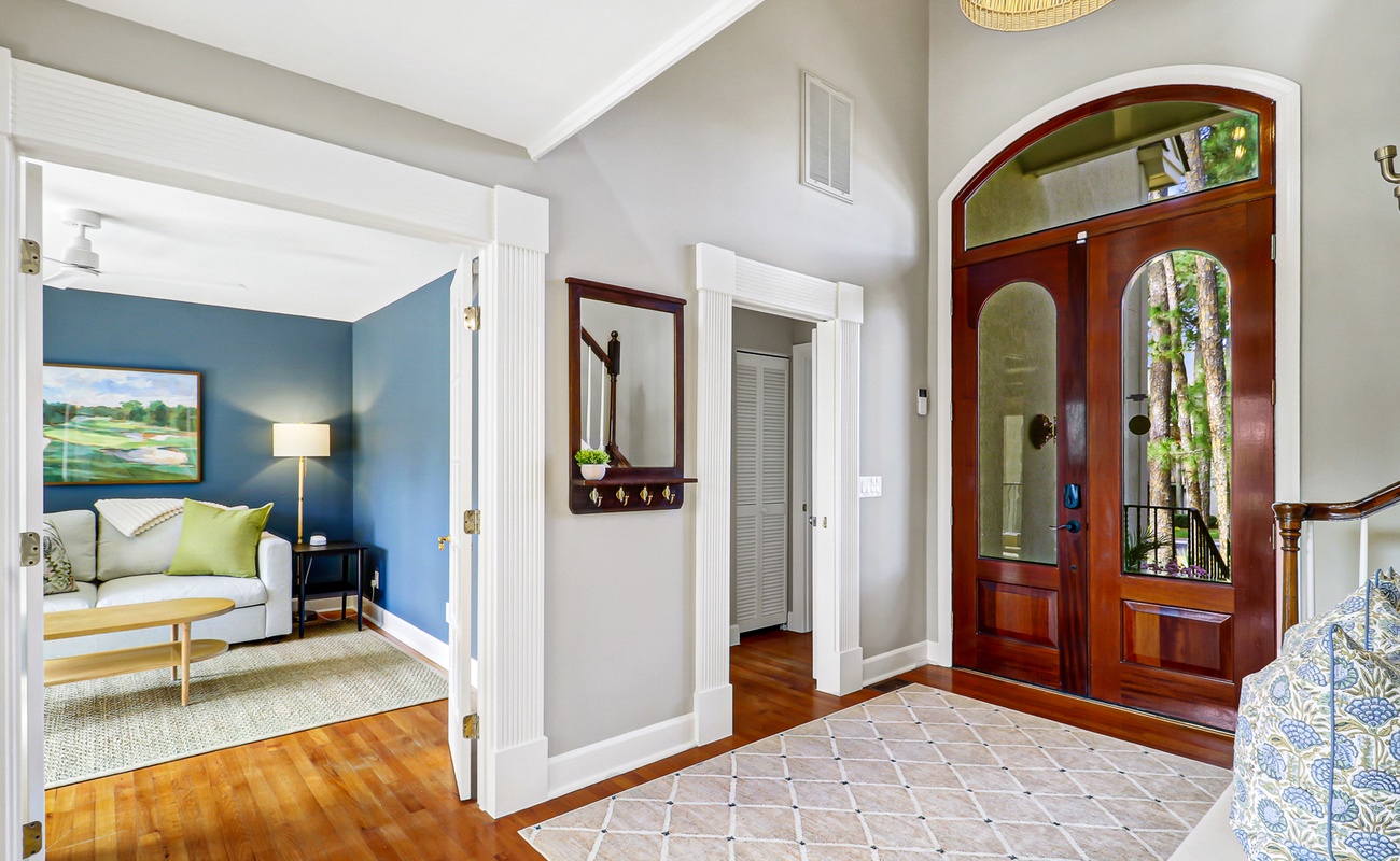 Step into your elegant entryway with rich hardwood floors and beautiful natural light streaming through stained glass doors.