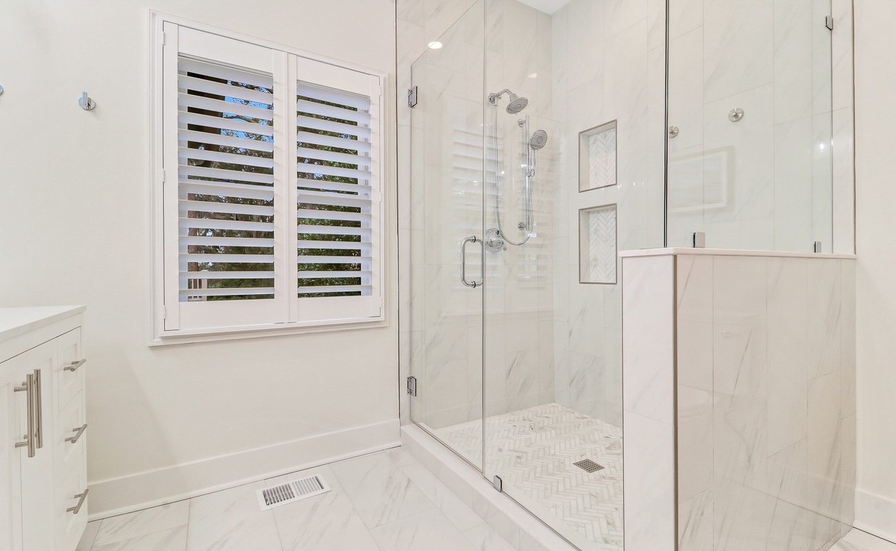 Step into your pristine marble bathroom featuring a luxurious glass-enclosed shower with dual fixtures for your ultimate comfort.