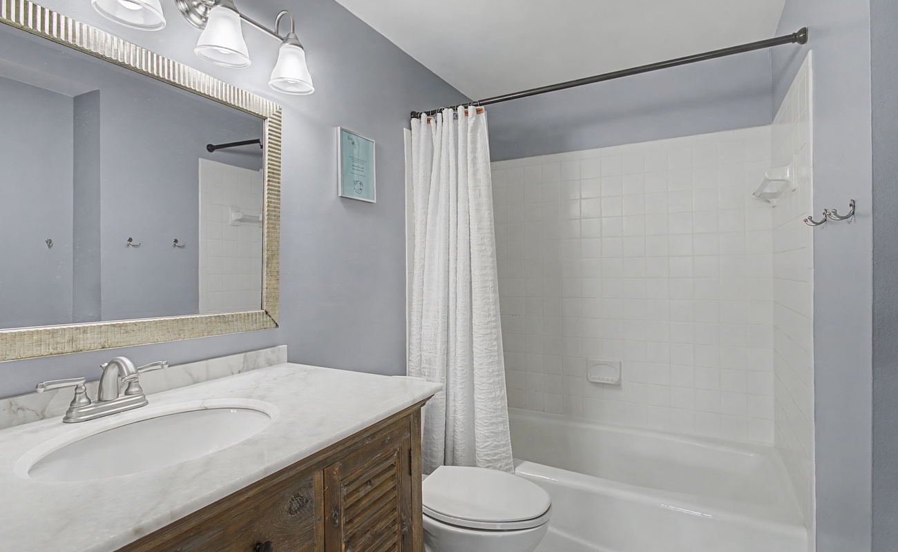 Your private bathroom features marble countertops, a spacious shower-tub combo, and coastal-inspired finishes for your relaxing getaway.