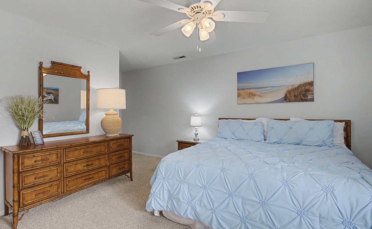 Drift off peacefully in your coastal-themed bedroom with soft blue linens and calming beach artwork creating the perfect seaside sanctuary.