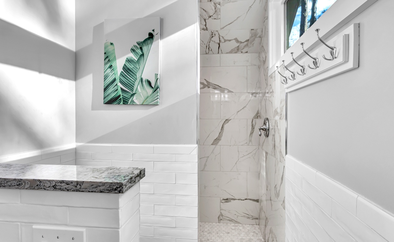 Your luxurious marble shower awaits with elegant finishes and tropical artwork creating a spa-like retreat.