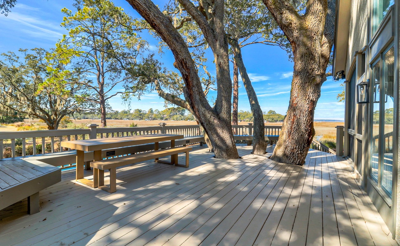 Step onto your private deck where ancient oaks create natural shade above wooden benches, perfect for morning coffee with marsh views.