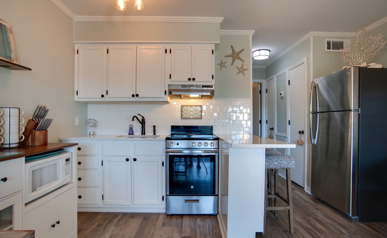 Your coastal-inspired kitchen features crisp white cabinets, subway tile backsplash, and modern stainless appliances, perfect for preparing meals.