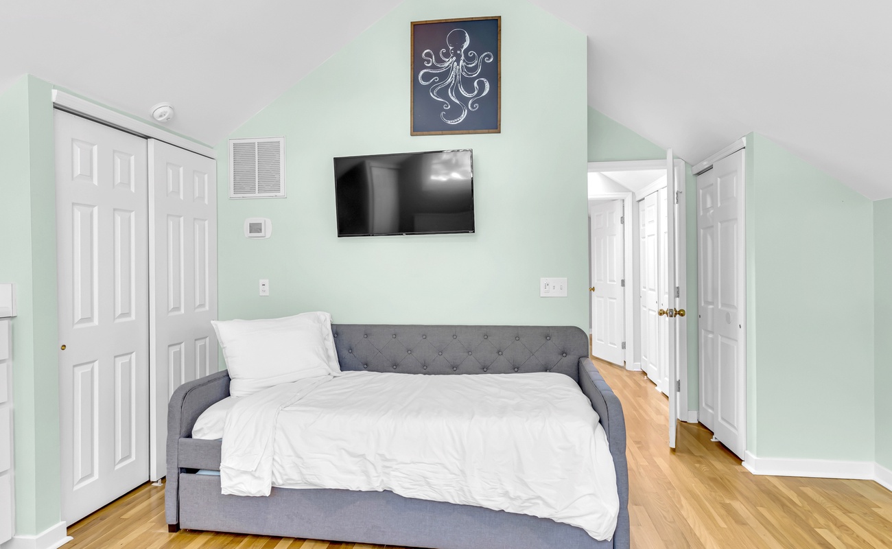 Relax in your tranquil bedroom featuring a cozy daybed, wall-mounted TV, and soothing mint green walls that create the perfect retreat.