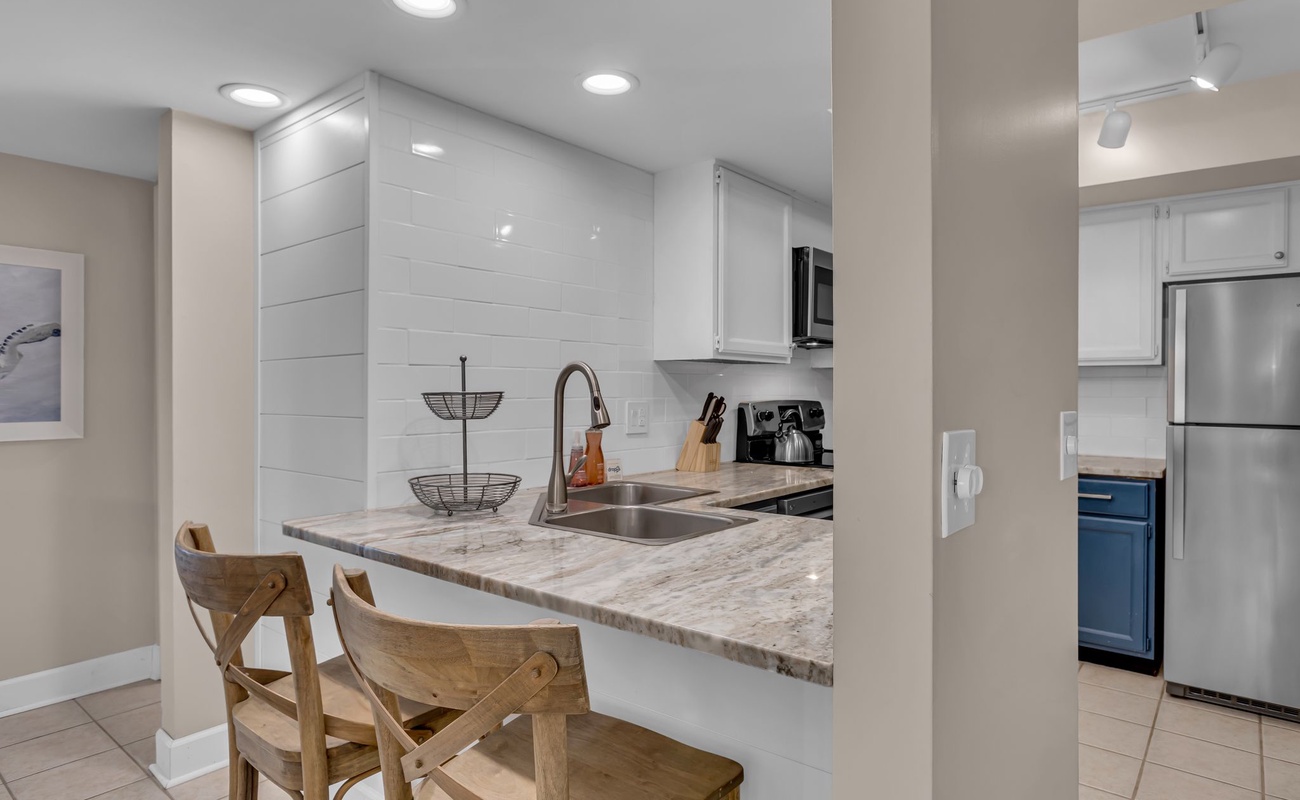 Your sleek kitchen features marble countertops and modern appliances, perfect for preparing meals and casual dining at the breakfast bar.