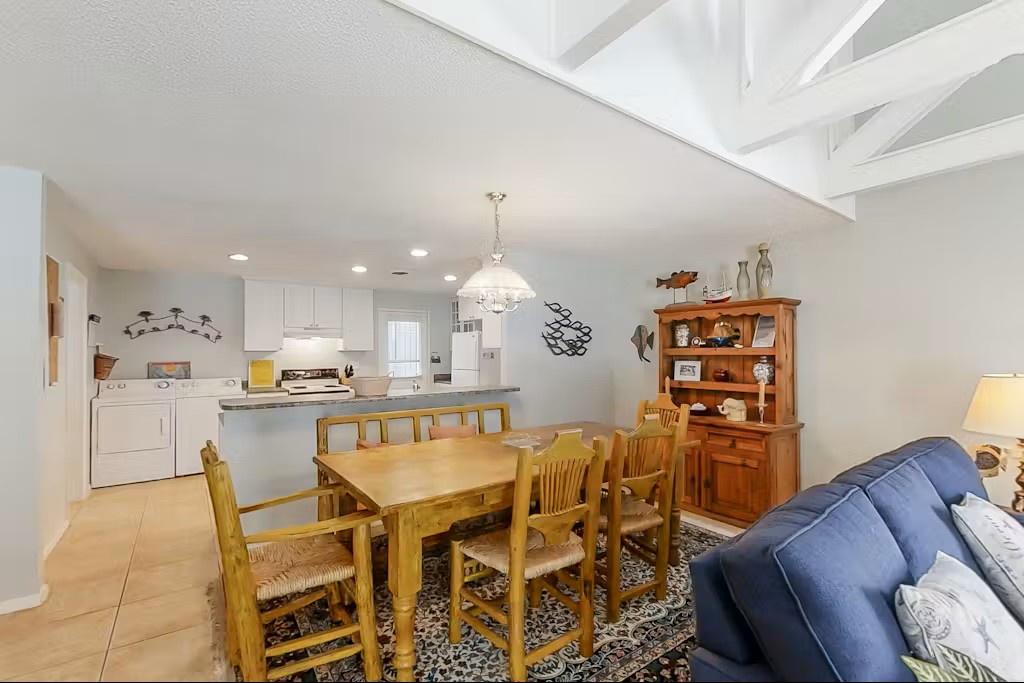 Your open-concept living space invites gathering with vaulted ceilings and warm wood dining table perfectly positioned for family meals and conversation.