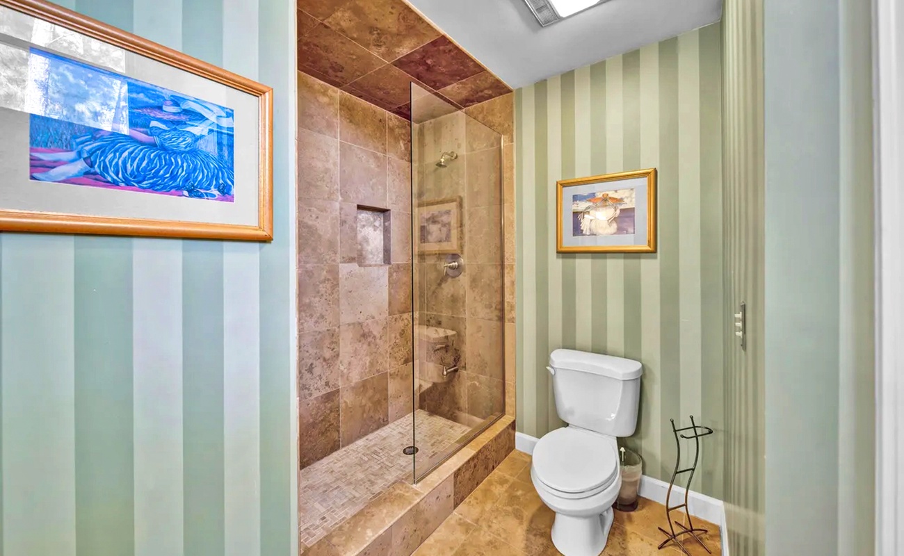 Step into your beautifully appointed bathroom with luxurious stone shower and elegant striped wallpaper creating a spa-like retreat.