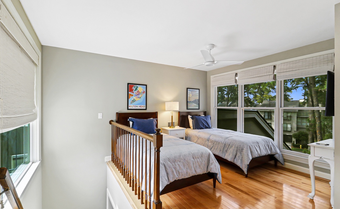 Relax in your bright bedroom with twin beds, hardwood floors, and peaceful tree views from large windows.