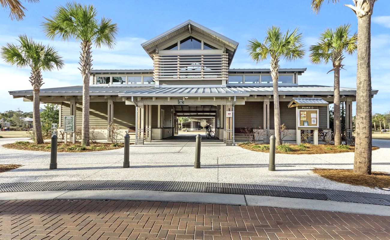 Modern community building featuring contemporary architecture with metal roofing and natural landscaping, surrounded by tropical palm trees.
