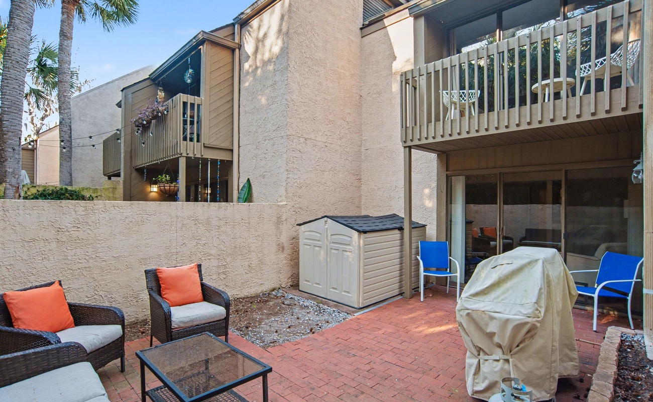 Relax in your private brick patio with comfortable outdoor seating, perfect for morning coffee or evening gatherings under swaying palm trees.