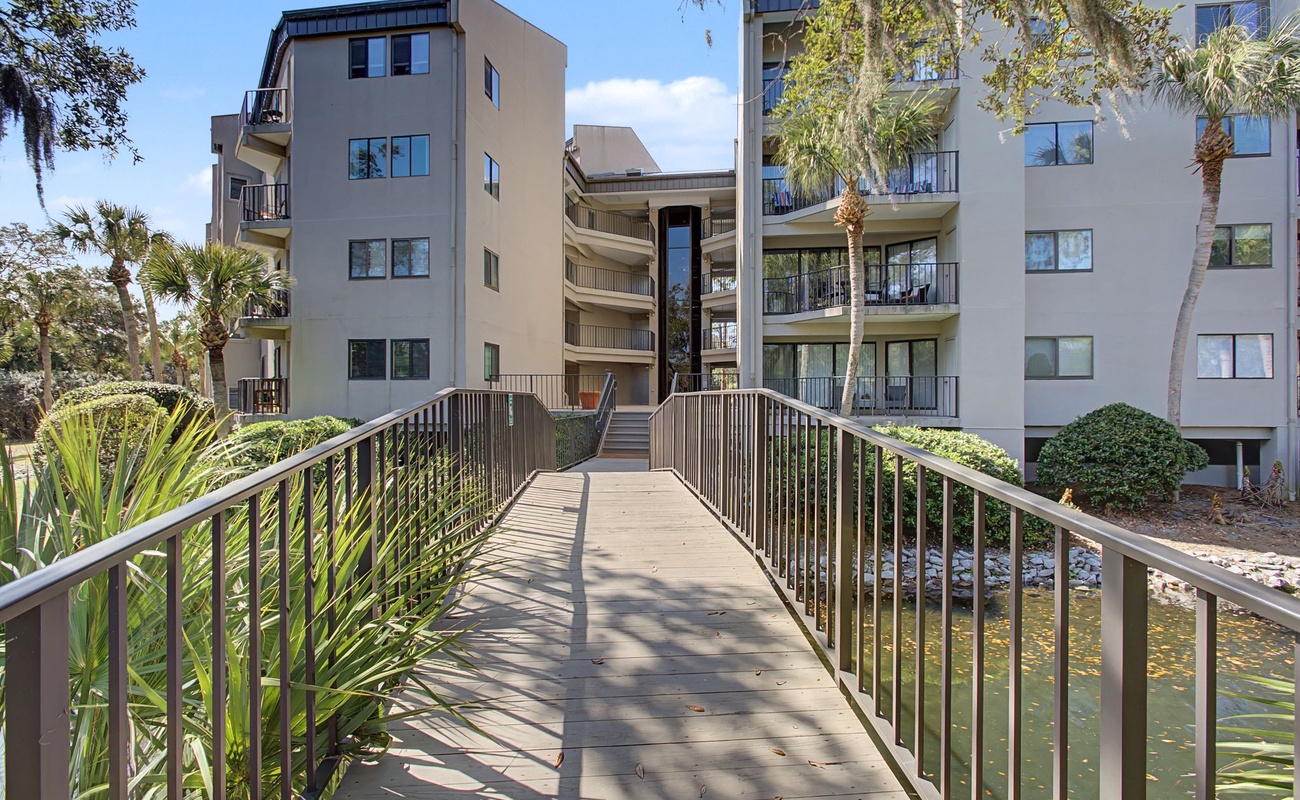 Modern beachside complex with lush tropical landscaping and charming bridge entrance creates a welcoming arrival experience.