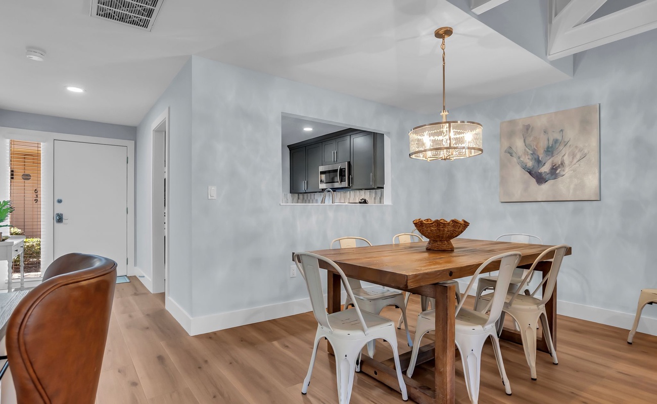 Gather around your rustic wooden dining table beneath crystal chandelier light, where memorable meals await in this modern coastal-chic space.